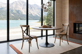 Two Castelmola dining chairs in Natural Rustic at a round table on a black base in a Carcross house, with spruce boards