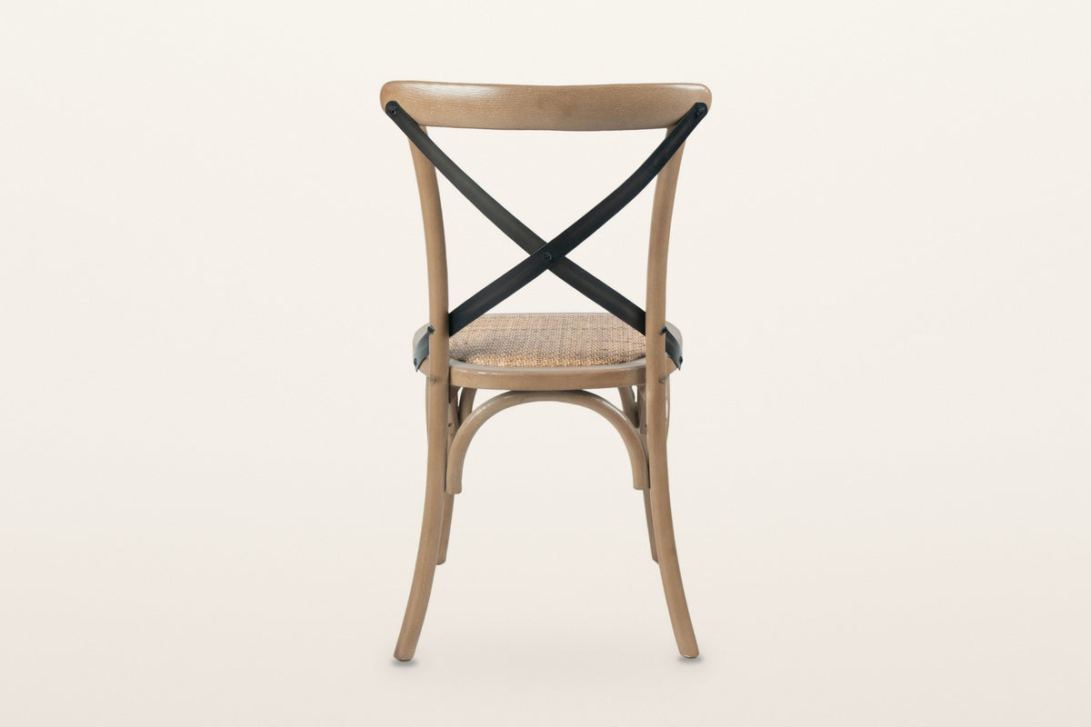 The back of the Castelmola dining chair in Sundried on a warm white studio backdrop: two flat iron straps crossing in an X