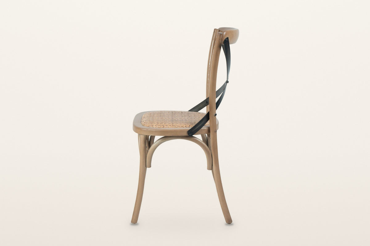 Castelmola dining chair in Sundried, side view on a warm white studio backdrop: the back post curves back above the seat