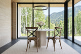Two Castelmola dining chairs in Sundried seen from behind at a round stone pedestal table in a Valemount house