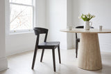 Two Certosa dining chairs in mocha at a round travertine pedestal table in a Toronto dining room