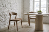 Two Certosa dining chairs in walnut at a round limestone table in an old Quebec City stone house