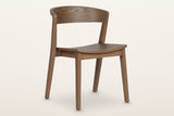 Certosa dining chair in walnut, three-quarter view on a warm white studio backdrop