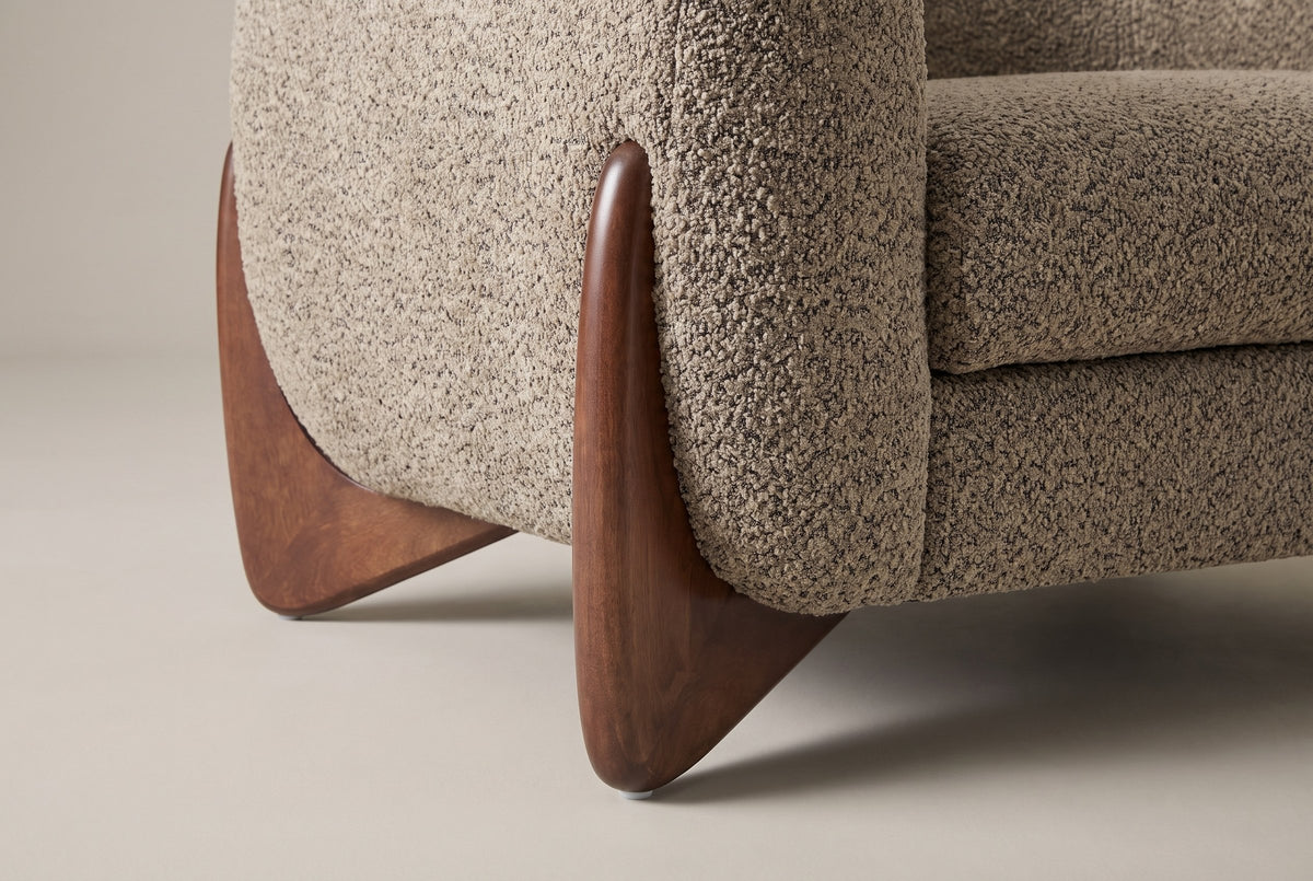 Close-up of a carved triangular birch leg in walnut finish at the corner of the Cervia arm