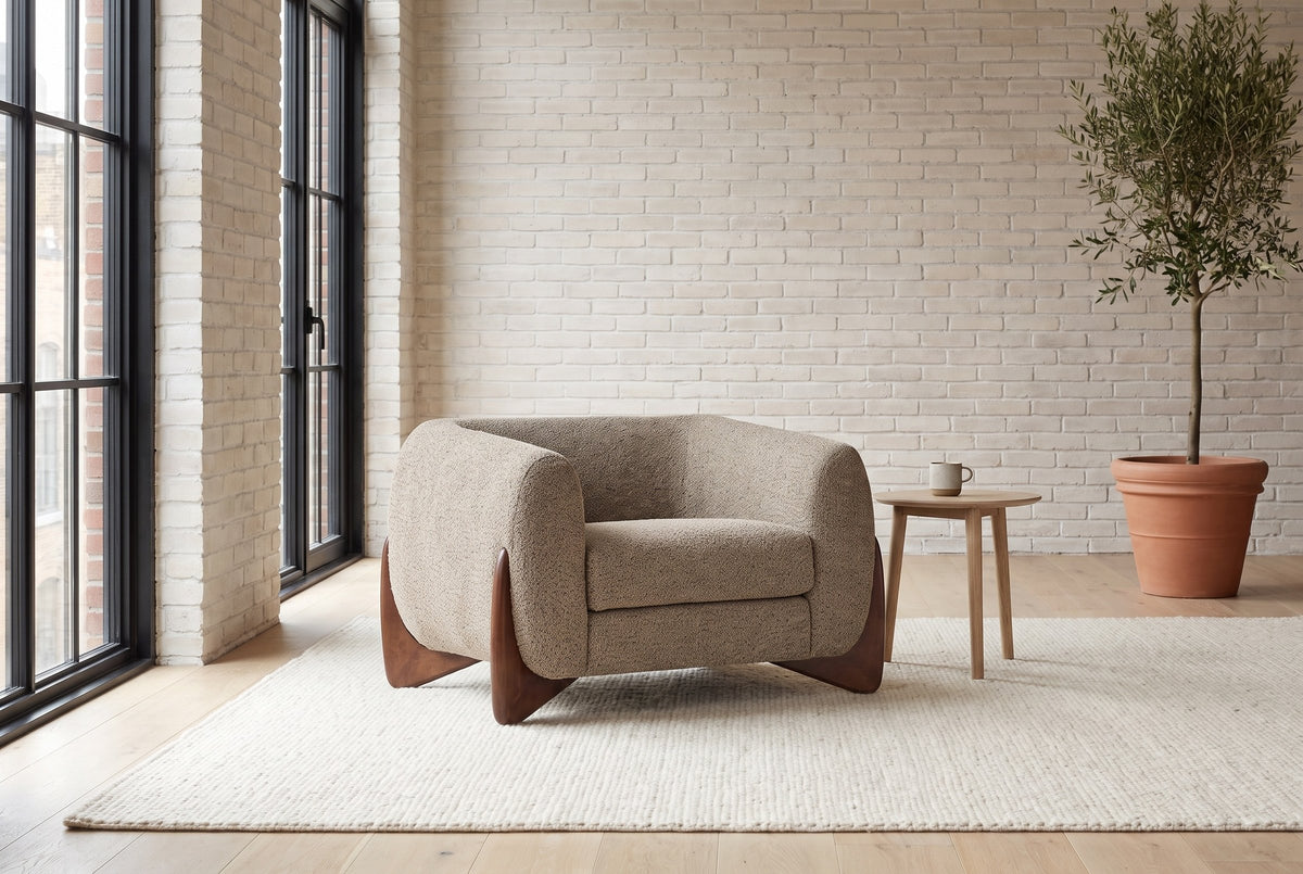 Cervia lounge chair in a bright Montreal loft with whitewashed brick, an ivory rug and an olive tree