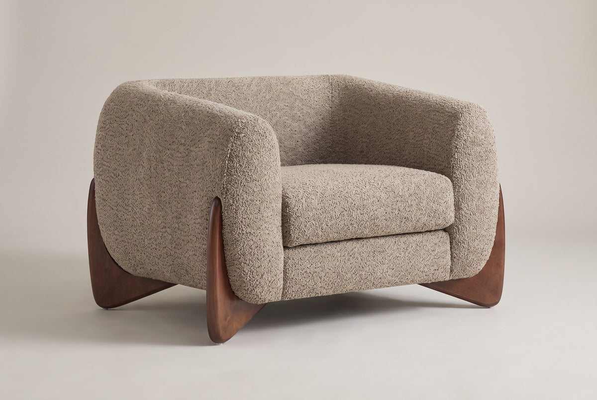 Cervia boucle lounge chair in Light Brown, three-quarter view on a warm grey studio backdrop
