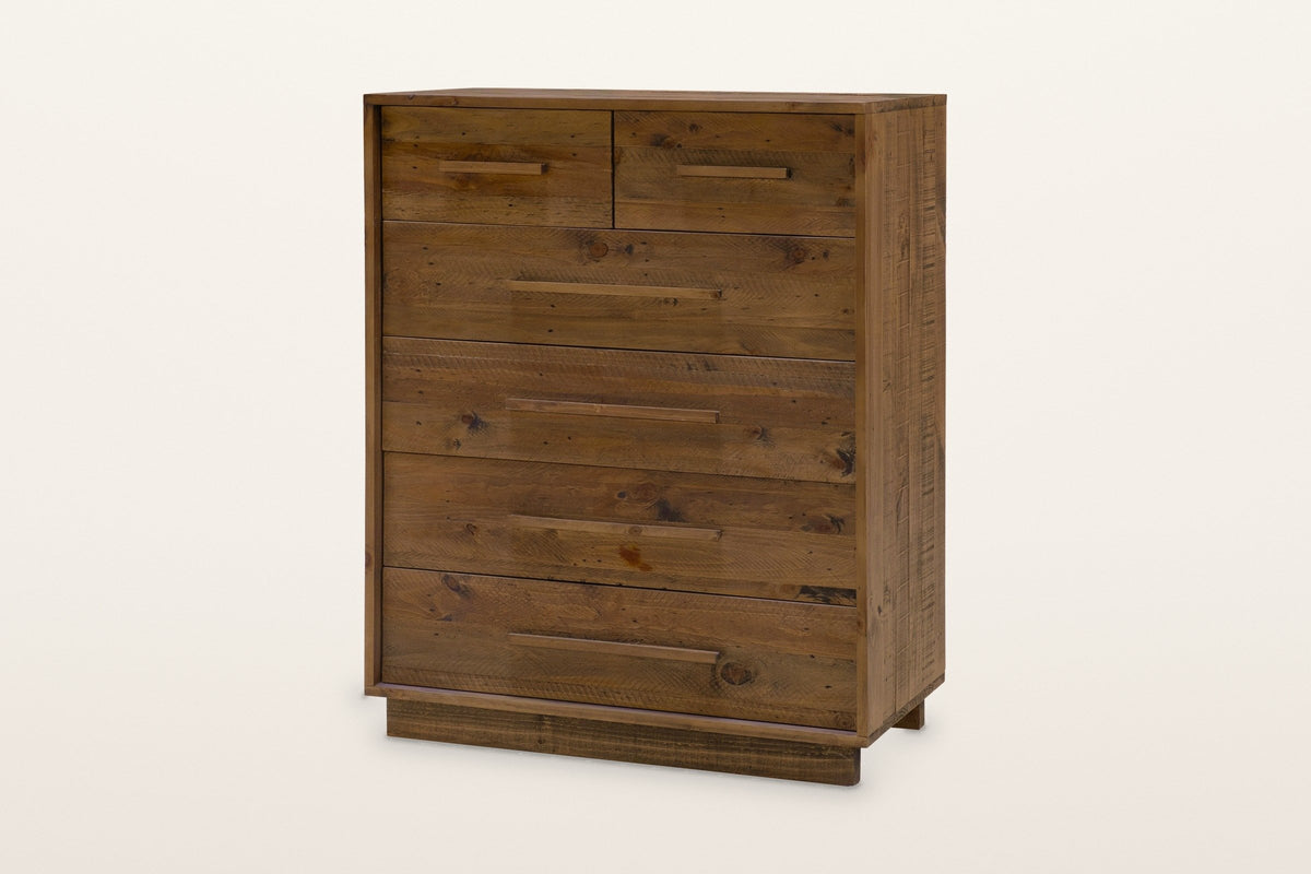 Cervinia tall chest in weathered brown reclaimed pine: two small drawers over four wide drawers, six wooden bar pulls, on a low recessed plinth, three-quarter view on a warm white studio backdrop