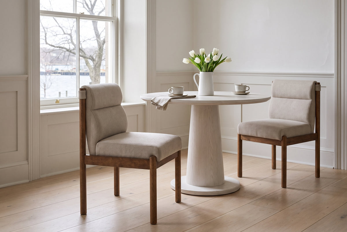 Two Cervo dining chairs in beige and walnut at a round white-oiled oak pedestal table in a Halifax dining room with white pan