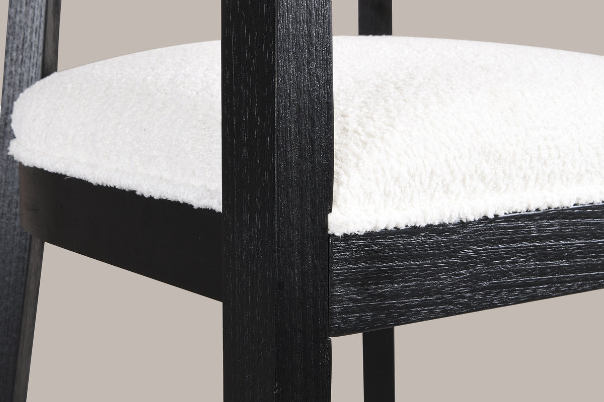 Close-up of the ivory boucle-look seat, the black wood seat frame and a tapered front leg of the Black Cesena chair