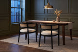 Two Cesena dining chairs in Black at a dark walnut table in an olive-green Toronto dining room at dusk
