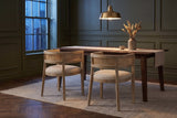 Two Cesena dining chairs in Natural Ash at a dark walnut table in an olive-green Toronto dining room at dusk