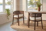Two Cesena dining chairs on a round jute rug in a Muskoka cottage dining nook with a view of the lake