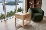 Cetara side table in Natural ash and wicker seen from above beside a forest-green boucle chair in a Prince Rupert house