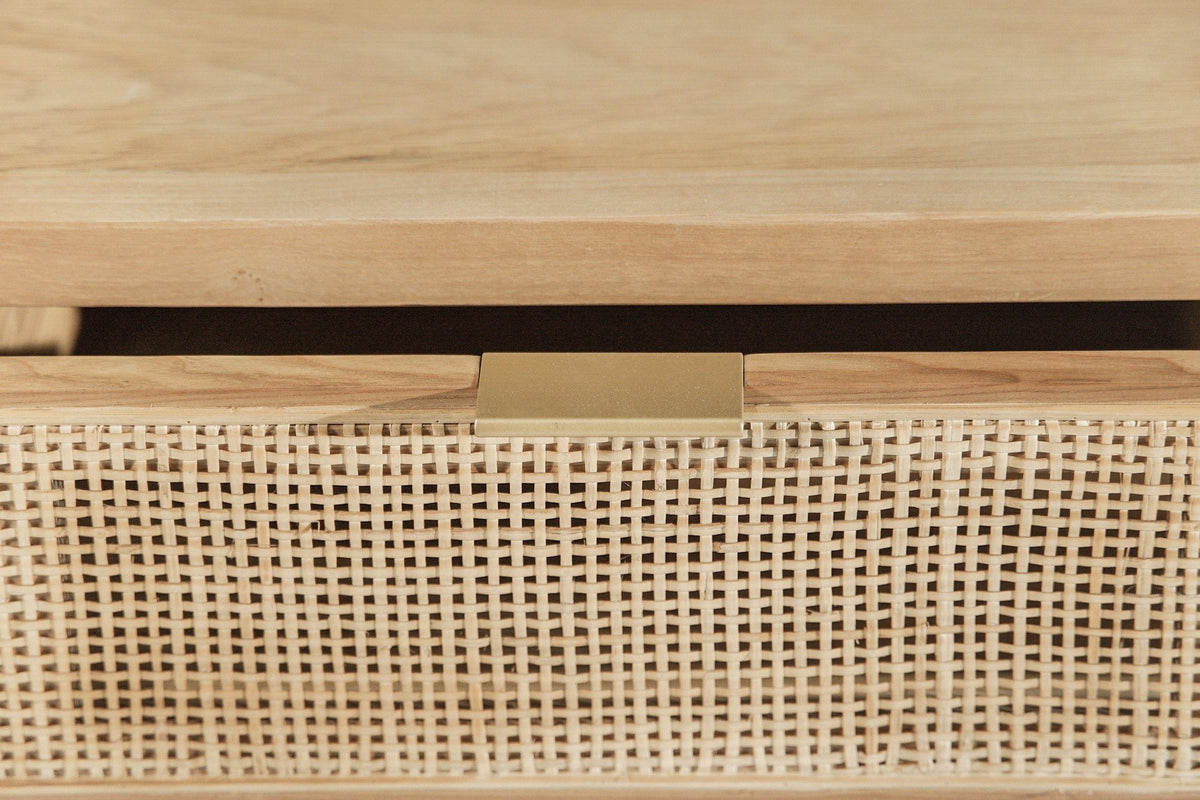Close-up of the Cetara drawer front: the ash top edge, the slim antique brass pull and the open square weave of the wicker