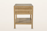 Side view of the Cetara side table in Natural on a warm white studio backdrop: one framed wicker panel under the top