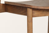 Close-up of the Chiavenna seat in walnut: the moulded seat with its layered edge on a plain apron, a round leg below