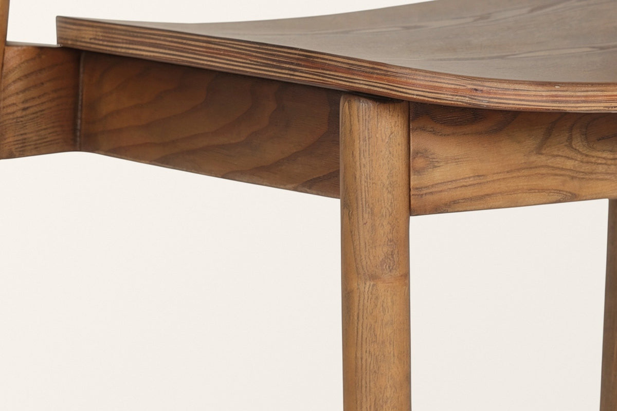 Close-up of the Chiavenna seat in walnut: the moulded seat with its layered edge on a plain apron, a round leg below