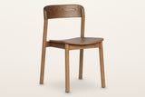 Chiavenna curved-back dining chair in walnut, three-quarter view on a warm white studio backdrop