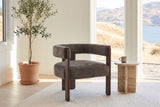 Chioggia accent chair in Dark Brown by a lake-view window with a travertine side table and an olive tree