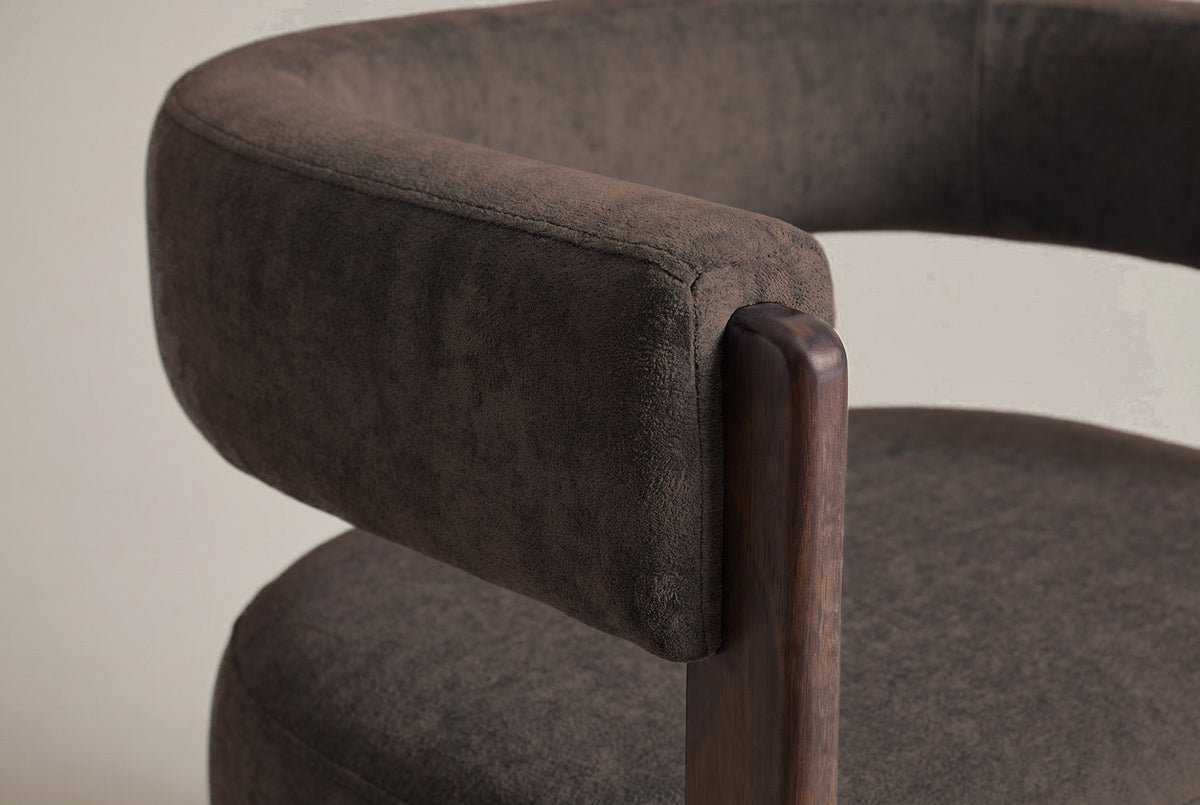 Close-up of the dark brown velvet back band ending on the rounded top of a walnut front leg