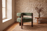 Chioggia accent chair against a limestone wall on pine floorboards and a jute rug (Olive Green)