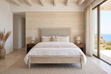 Front view of the Chiusdino bed in a bedroom in an Aljezur cliff house in Portugal, with a travertine wall