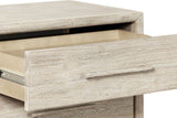 Close-up of a Chiusdino drawer pulled out under the rounded top edge, with its slim bar pull and the whitewashed grain