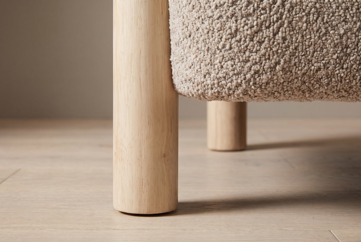 Close-up of a round natural rubberwood leg beside the rounded boucle seat
