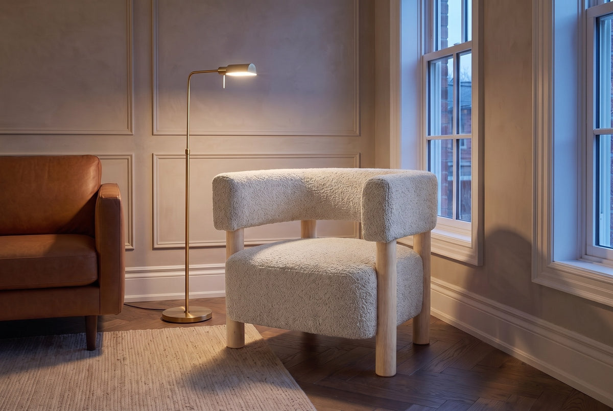 Cingoli chair beside a cognac leather sofa in an Ottawa townhouse living room at dusk, a brass floor lamp lit (Wheat)