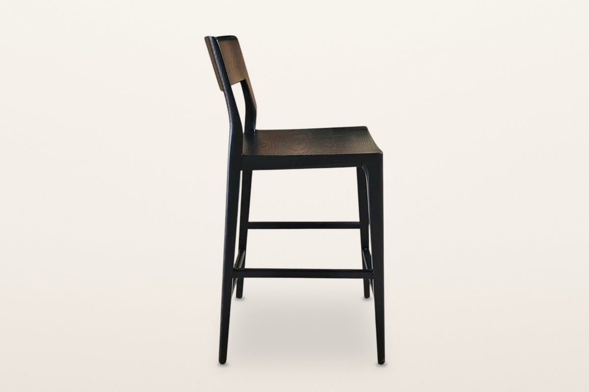 Cison counter stool in Black, side view on a warm white studio backdrop