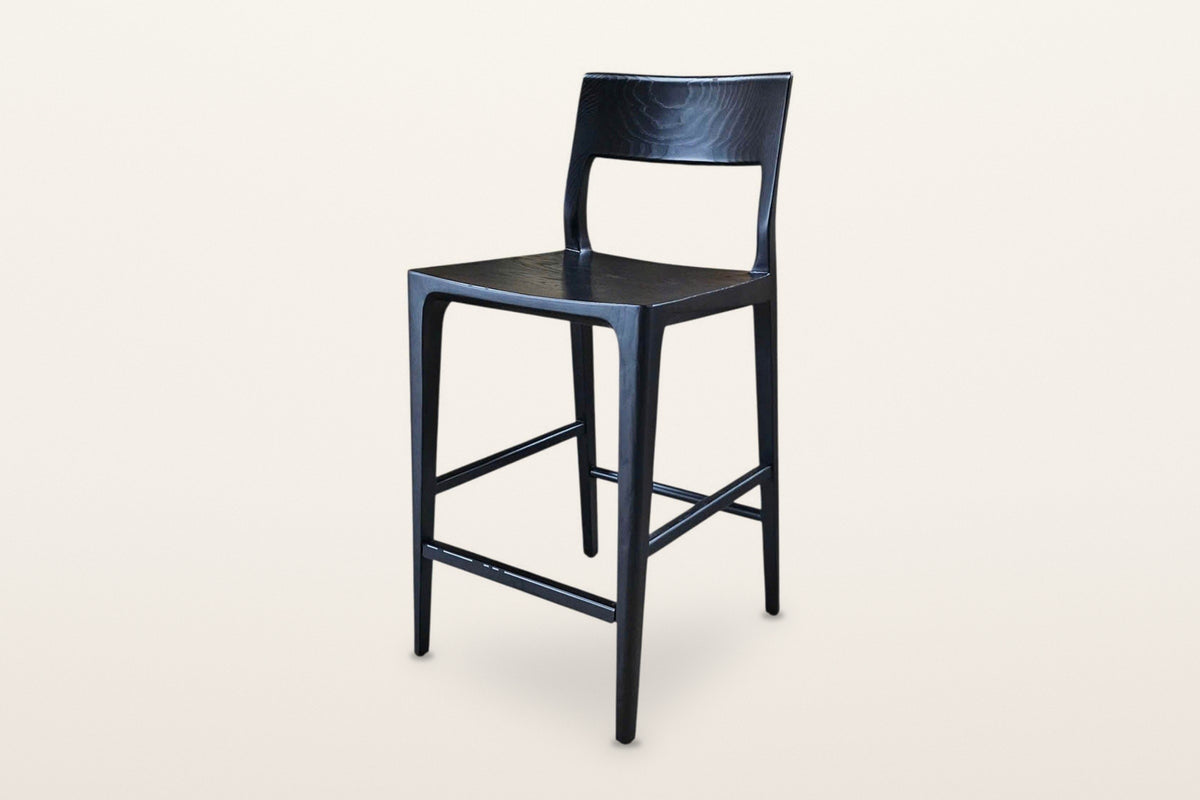 Cison solid ash counter stool in Black, three-quarter view on a warm white studio backdrop: black ash with a black metal foot