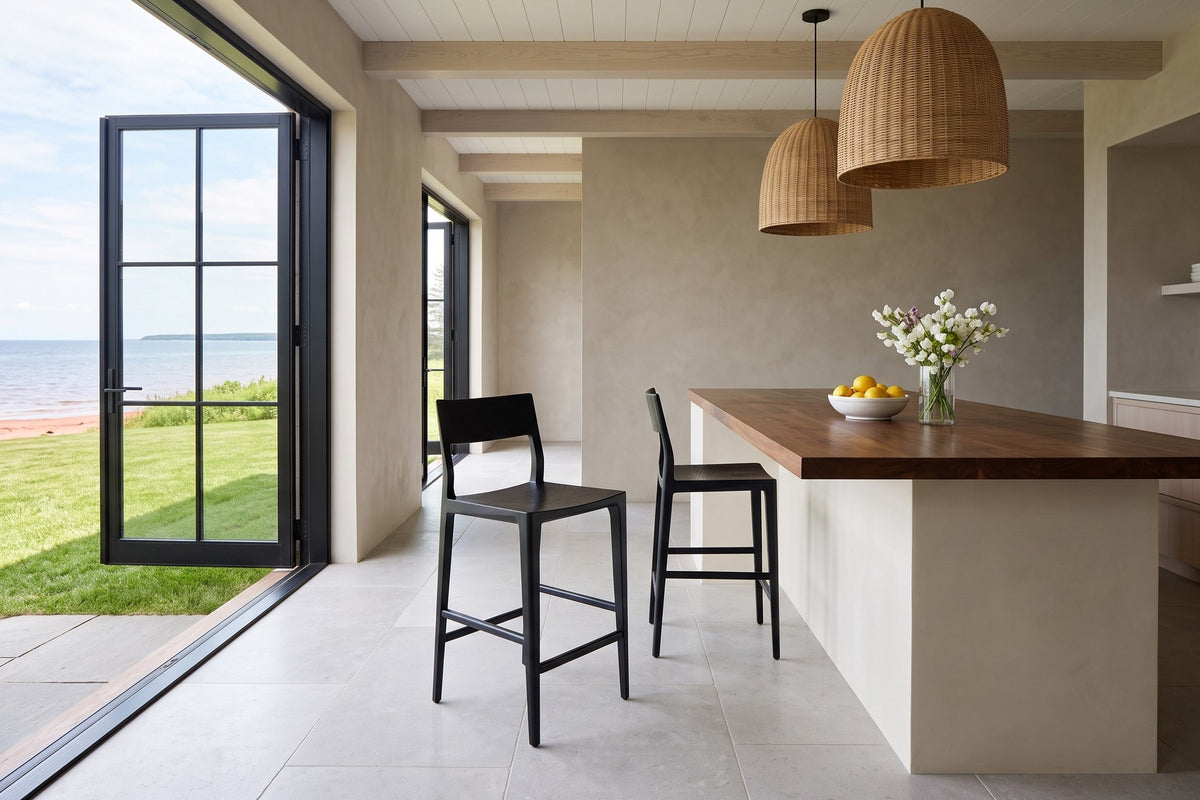 Two Cison counter stools in Black at a walnut-topped island in a Tatamagouche seaside house, with greige plaster