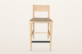 Cison counter stool in Natural, straight front view on a warm white studio backdrop: the curved backrest