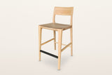 Cison solid ash counter stool in Natural, three-quarter view on a warm white studio backdrop: a curved ash backrest on two sl