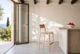 A Cison counter stool in Natural in side profile beside a travertine island in a Taormina villa