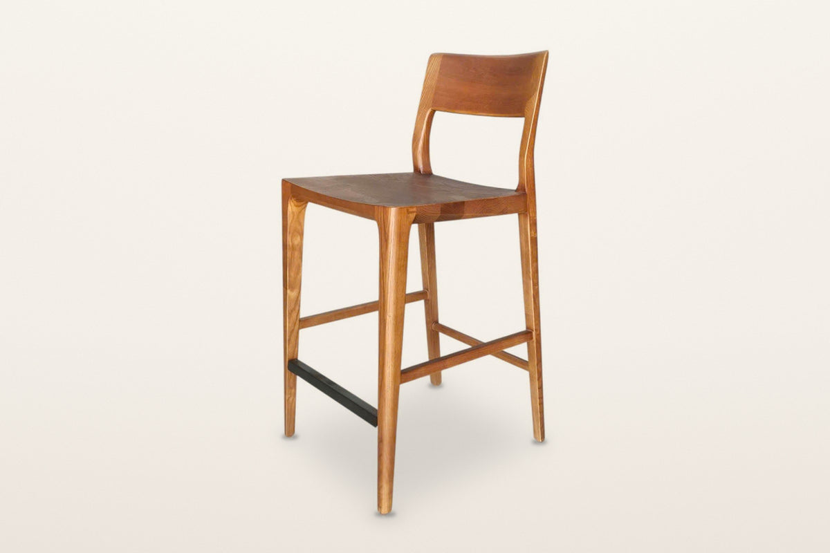Cison solid ash counter stool in Warm Brown, three-quarter view on a warm white studio backdrop: warm brown ash with a black