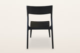 Cison dining chair in Black, back view on a warm white studio backdrop: the backrest panel and the two posts