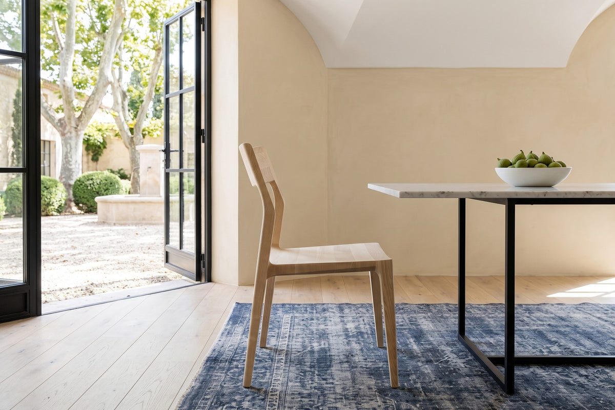 A Cison dining chair in Natural in side profile beside a marble table in an Aix-en-Provence bastide
