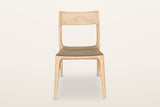 Cison dining chair in Natural, front view on a warm white studio backdrop: the wide backrest on top of the posts