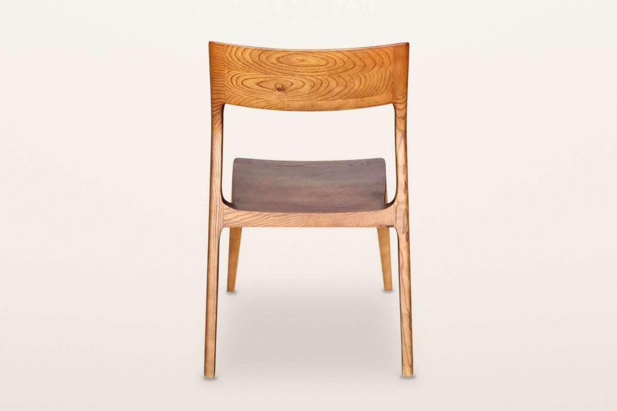 Cison dining chair in Warm Brown, back view on a warm white studio backdrop: the backrest panel and the two posts