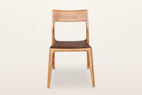 Cison dining chair in Warm Brown, front view on a warm white studio backdrop: the wide backrest on top of the posts