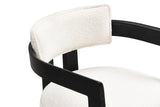 Close-up of the flat black arm rail curving round behind the slim ivory boucle back pad of the Cisternino chair