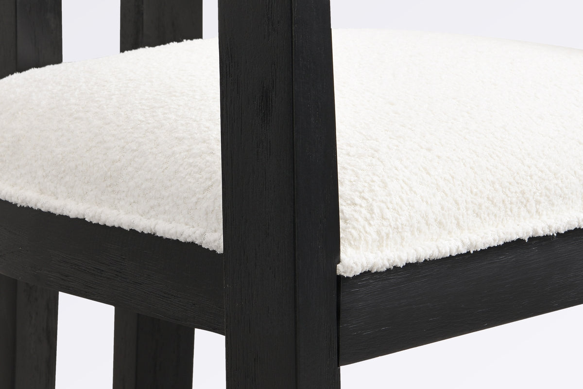 Close-up of the ivory boucle seat, the square front leg and the black wire-brushed wood frame of the Cisternino chair
