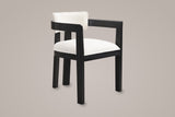 Cisternino dining armchair in Black with an ivory boucle seat, three-quarter view on a warm grey studio backdrop