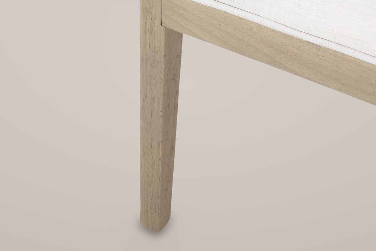 Close-up of a square tapered Civita leg under the seat frame and the piped edge of the linen-look seat