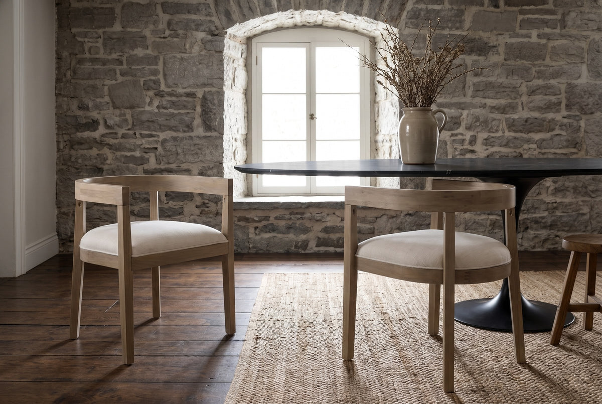 Two Civita dining chairs at a black stone-topped table in a Quebec City dining room with a rough limestone wall and an arched