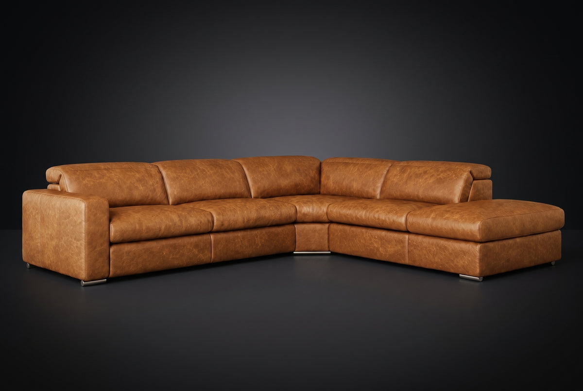 The Clara sectional against a dark studio backdrop, headrests down, the chaise on the right. Shown in distressed full-aniline leather, Antiqued Caramel, Right bumper.