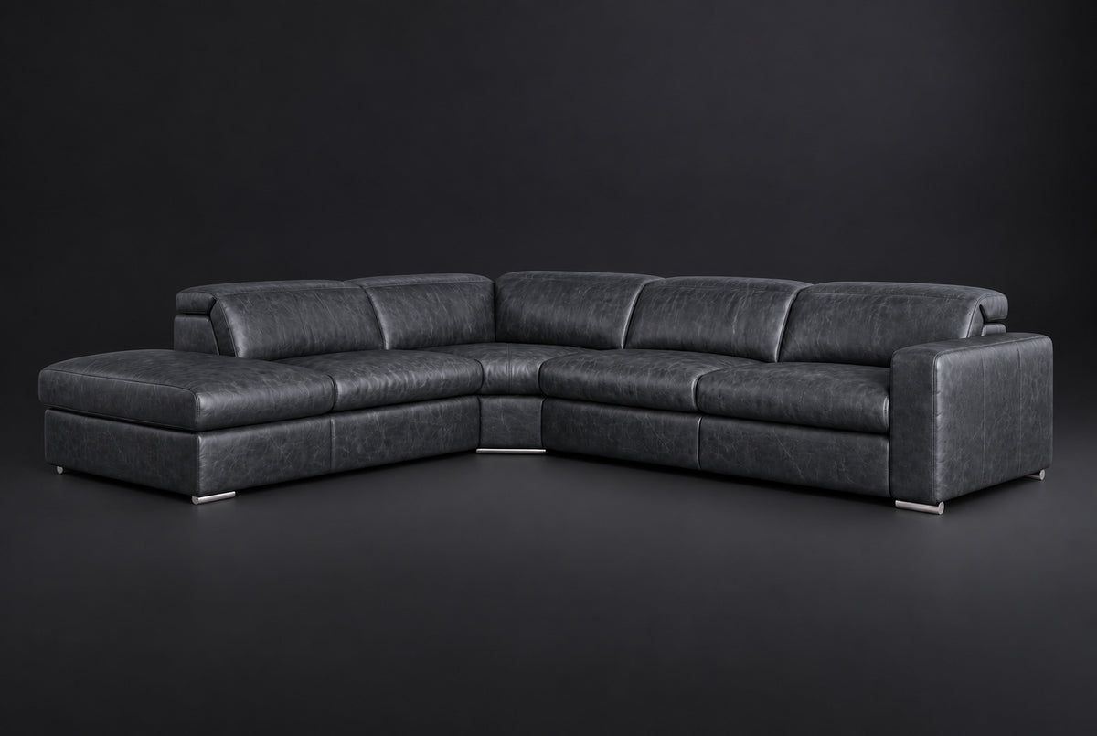 The Clara sectional against a dark studio backdrop, headrests down, the chaise on the left. Shown in distressed full-aniline leather, Aged Slate, Left bumper.