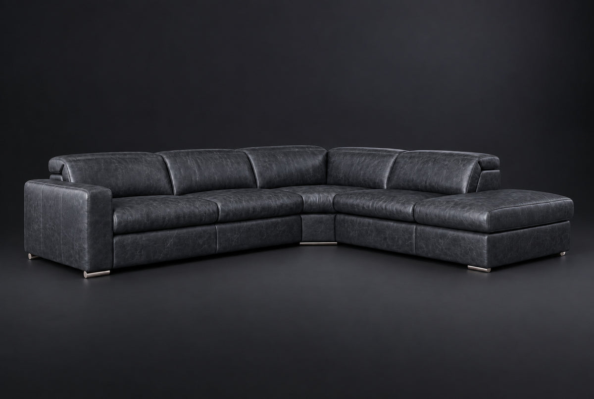 The Clara sectional against a dark studio backdrop, headrests down, the chaise on the right. Shown in distressed full-aniline leather, Aged Slate, Right bumper.