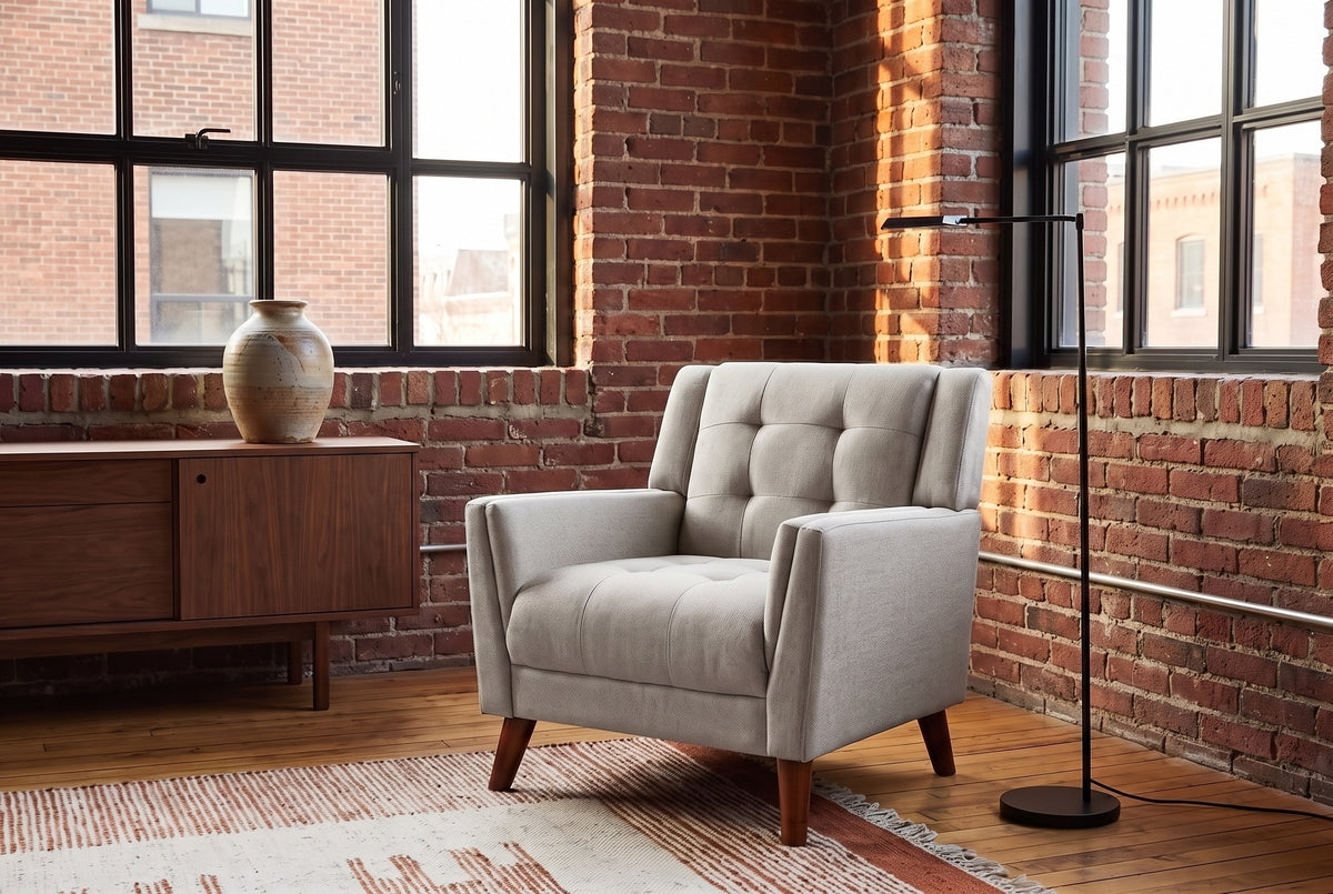 Comacchio armchair in beige in a brick-walled loft with steel windows, a walnut sideboard and a black floor lamp